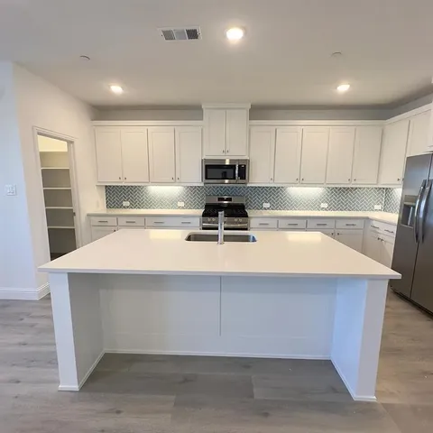 a kitchen with a sink a stove a refrigerator and white cabinets