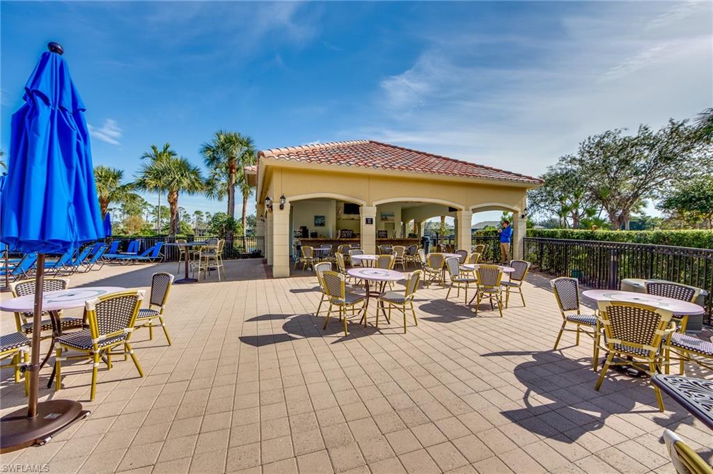 20060 Markward Crossing Estero, FL 33928 - Photo 48 of 50 a view of a patio with a dining table and chairs under an umbrella with large trees