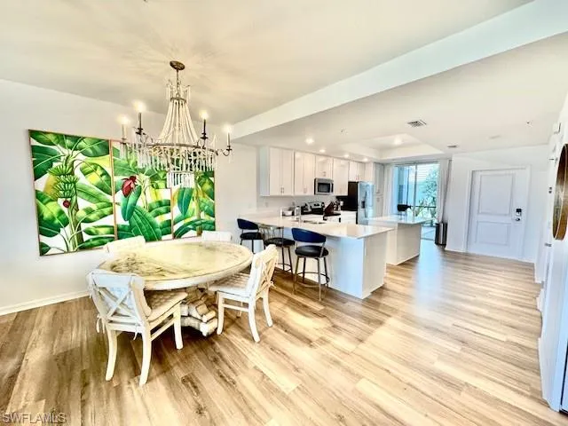 a view of a dining room and livingroom with furniture wooden floor a chandelier