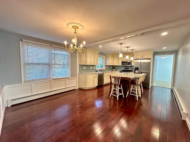 a kitchen with stainless steel appliances granite countertop a stove top oven a dining table chairs and chandelier