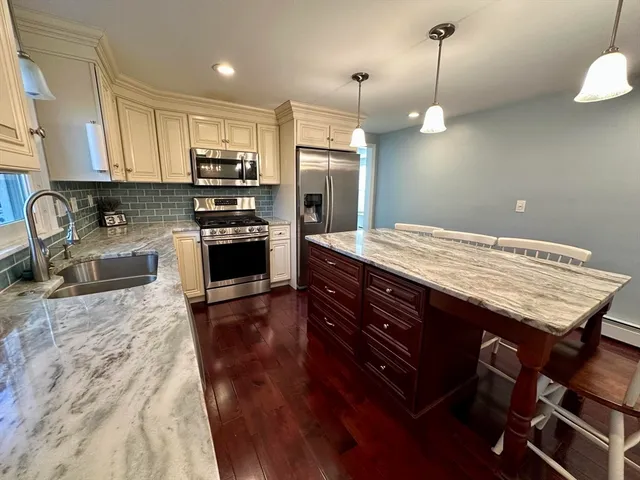 a kitchen with kitchen island granite countertop a stove a sink and wooden floor
