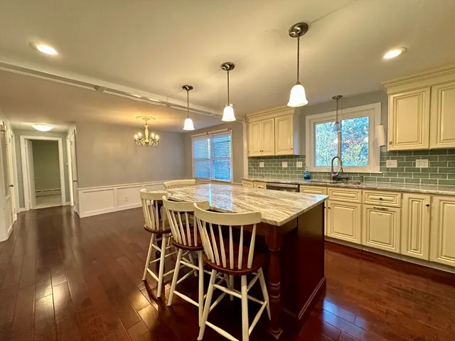 a kitchen with stainless steel appliances granite countertop a stove a refrigerator a kitchen island a sink and a wooden cabinets