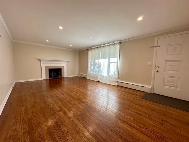 an empty room with wooden floor fireplace and windows