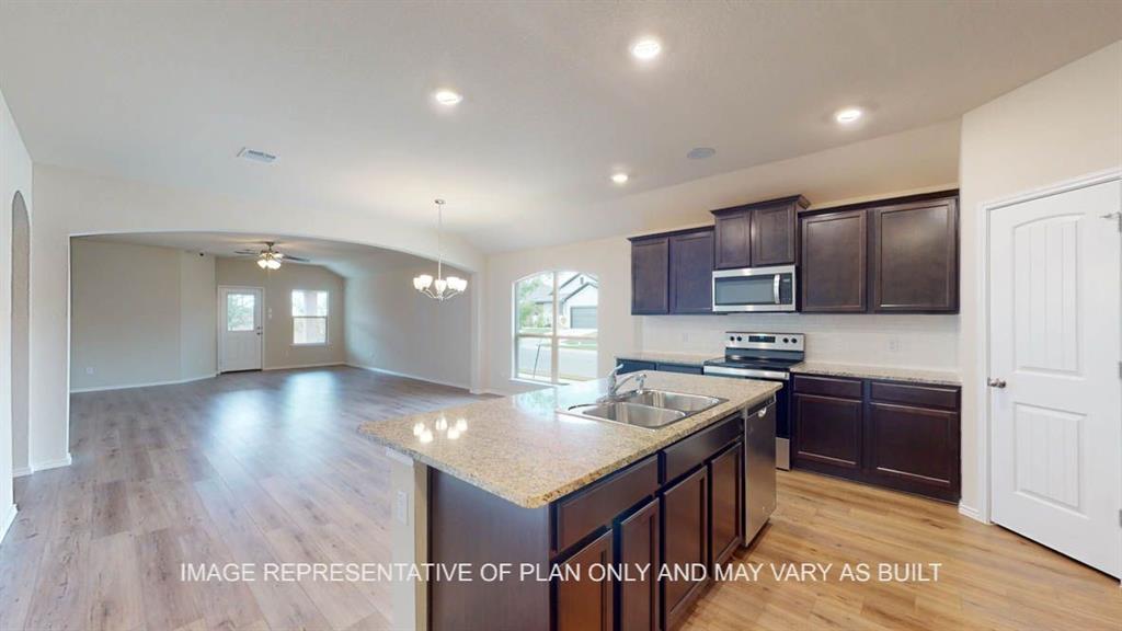 a kitchen with stainless steel appliances granite countertop a stove a sink a refrigerator and a microwave