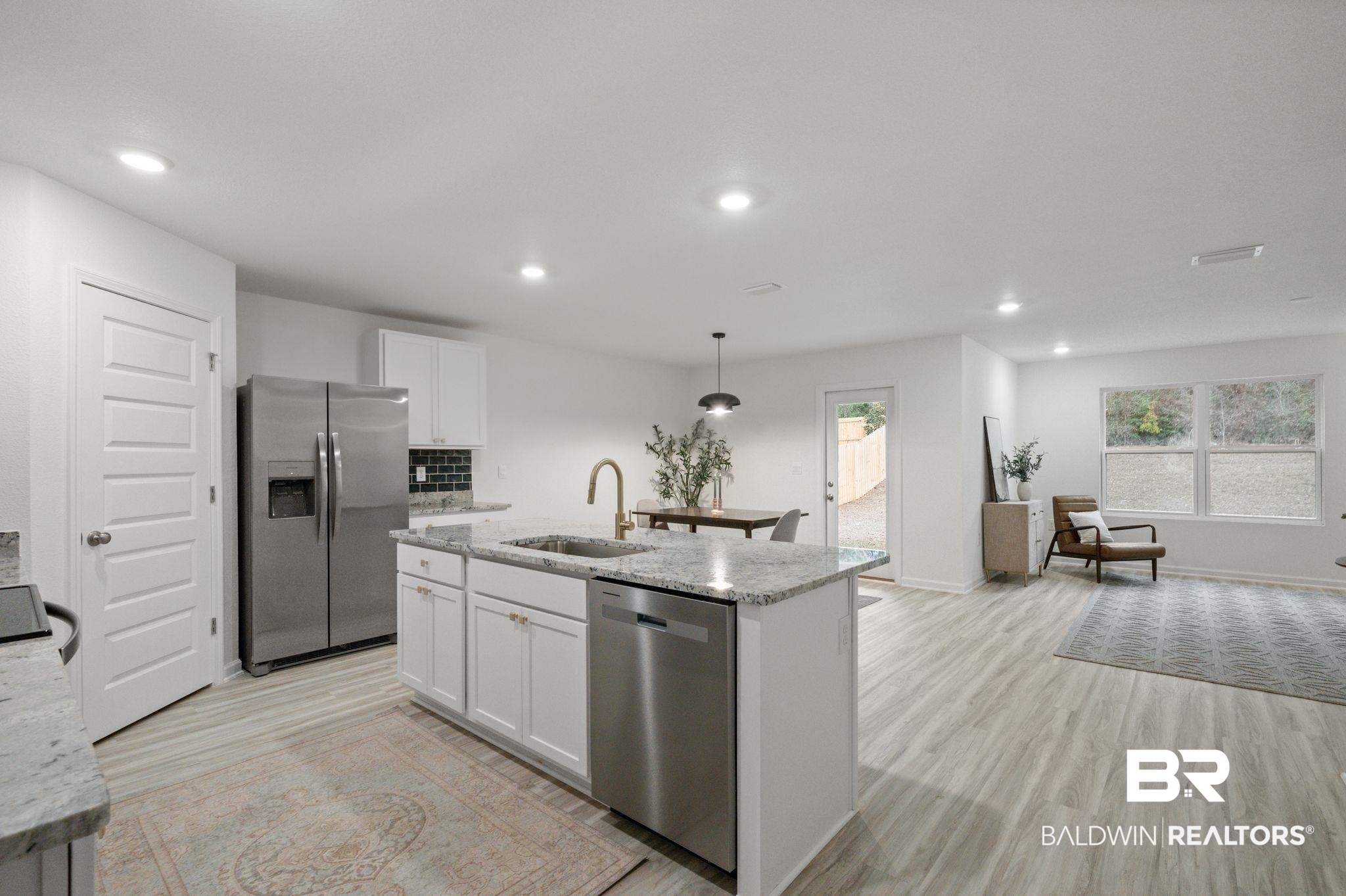 16272 Laurelbrooke Loop Fairhope, AL 36532 - Photo 9 of 40 Kitchen featuring white cabinetry, sink, light stone counters, stainless steel appliances, and a center island with sink