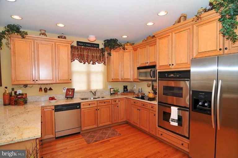 10019 German Road Ellicott City, MD 21042 - Photo 7 of 30 a kitchen with stainless steel appliances a sink dishwasher a refrigerator and cabinets with wooden floor