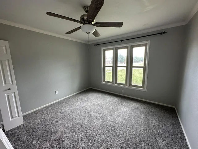 en empty room with windows and ceiling fan