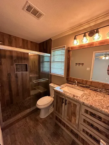 a bathroom with a granite countertop toilet and a shower