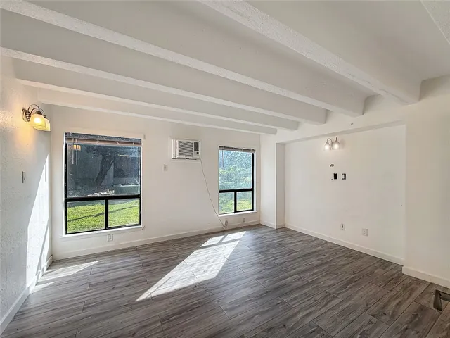 a view of an empty room with window and wooden floor