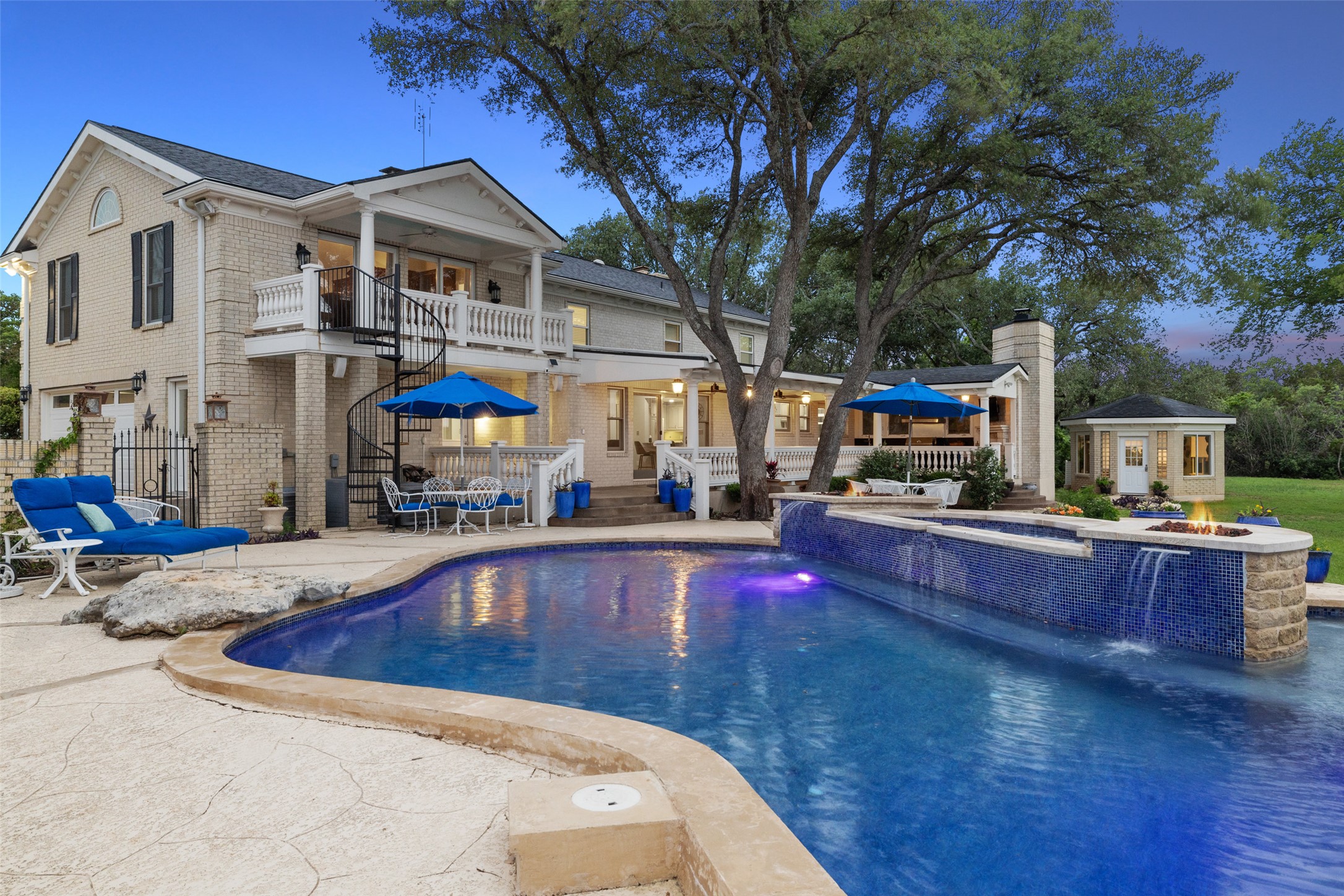 17700 North Rim Drive Leander, TX 78641 - Photo 1 of 38 Pool at dusk featuring an outdoor structure, a patio, stairs, a pool with connected hot tub, and fence