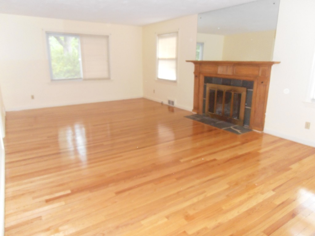 168 Emerson Street Springfield, MA 01118 - Photo 3 of 14 an empty room with wooden floor fireplace and windows