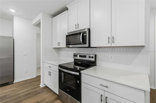 a kitchen with granite countertop white cabinets and stainless steel appliances