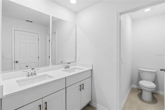 a bathroom with a toilet a sink a mirror and a window