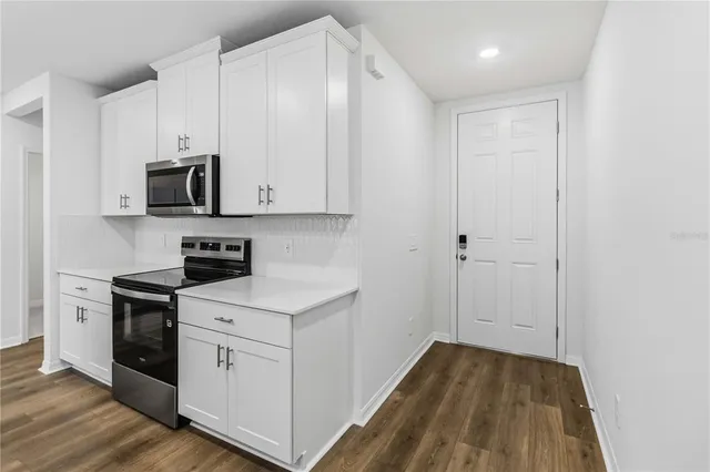 a kitchen with cabinets appliances and a wooden floor
