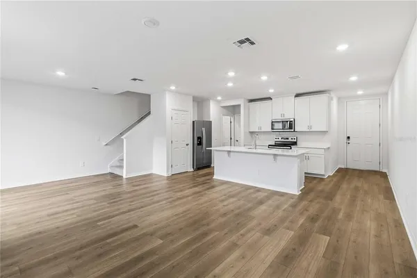 a view of kitchen with kitchen island sink refrigerator and white cabinets