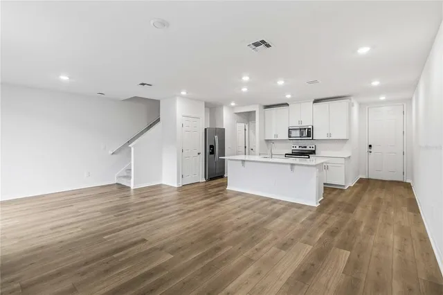 a view of kitchen with kitchen island sink refrigerator and white cabinets