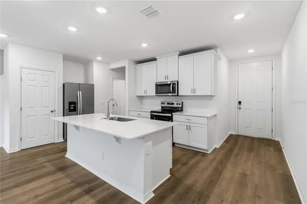 a kitchen with sink a microwave oven a refrigerator and white cabinets