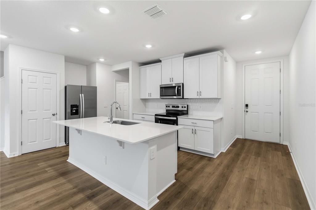 4571 Range Land Way St. Cloud, FL 34772 - Photo 10 of 43 a kitchen with sink a microwave oven a refrigerator and white cabinets