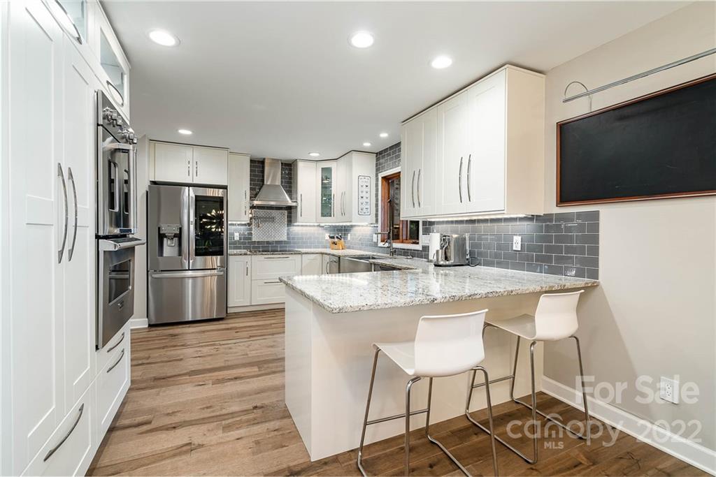 4525 Rounding Run Road Charlotte, NC 28277 - Photo 18 of 44 a kitchen with stainless steel appliances granite countertop a stove a sink a refrigerator and a oven with wooden floor