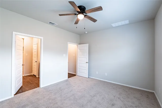 an empty room with closet and a chandelier fan