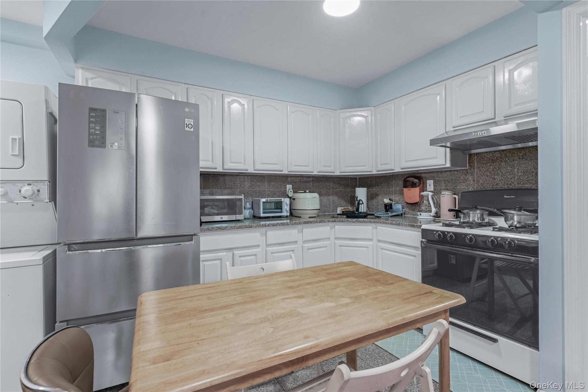 35-06 Leavitt Street, Unit 3K Queens, NY 11354 - Photo 4 of 17 Kitchen featuring stainless steel appliances, white cabinets, light stone counters, and decorative backsplash