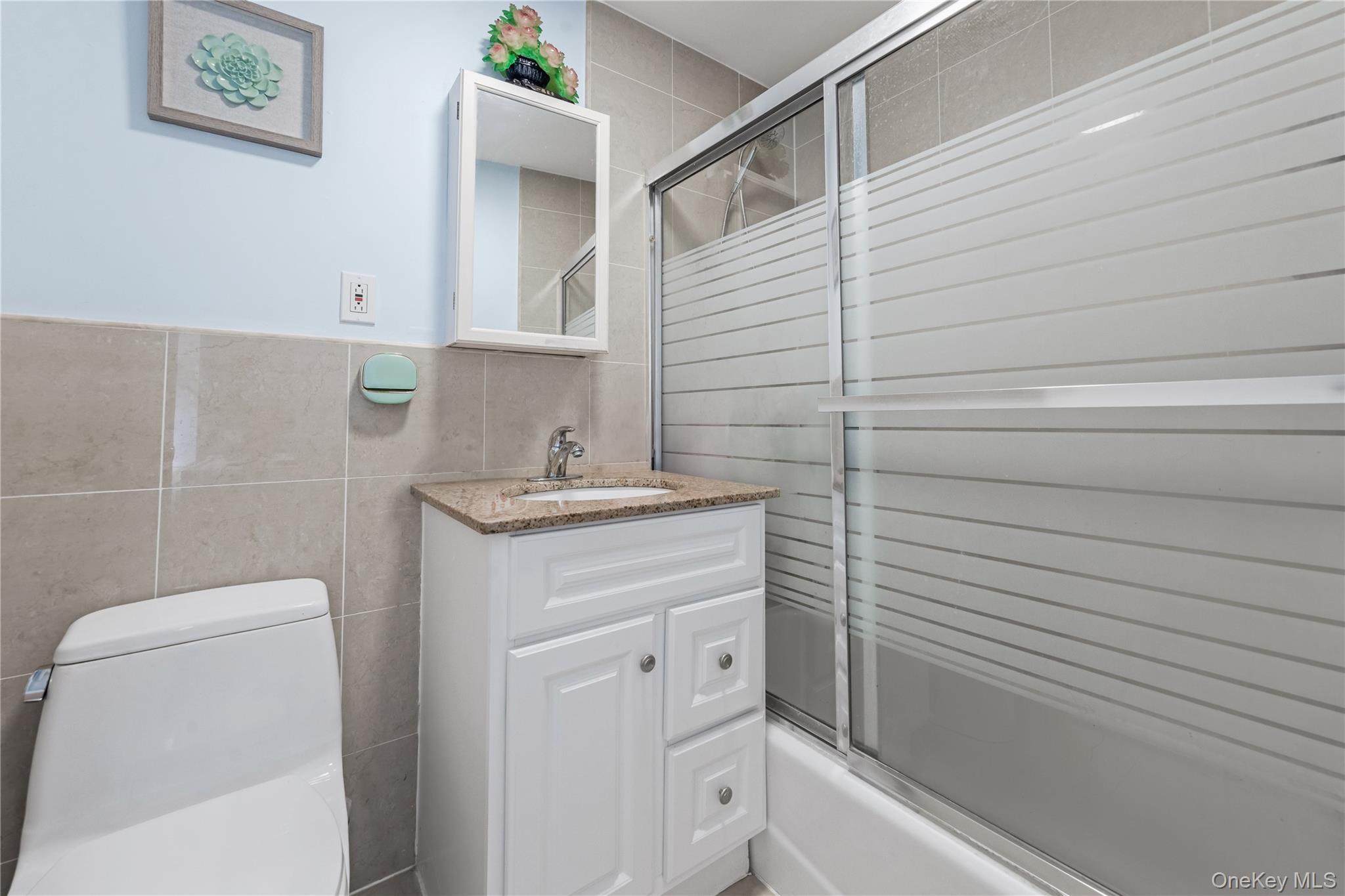 35-06 Leavitt Street, Unit 3K Queens, NY 11354 - Photo 9 of 17 Full bath featuring bath / shower combo with glass door, vanity, and tile walls