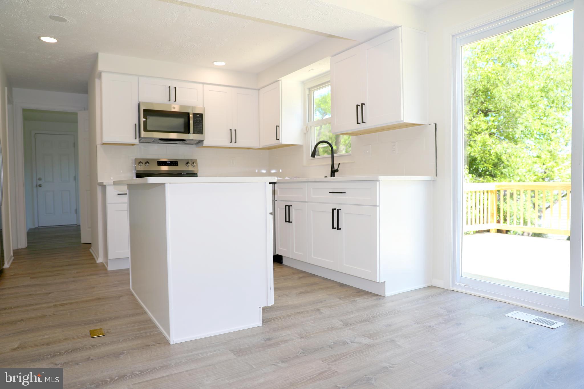 8106 Triple Crown Road Bowie, MD 20715 - Photo 3 of 21 a kitchen with stainless steel appliances a stove a sink a refrigerator white cabinets and wooden floor
