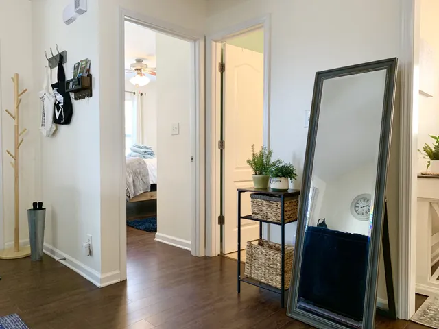 a view of a hallway with wooden floor and a livingroom with furniture