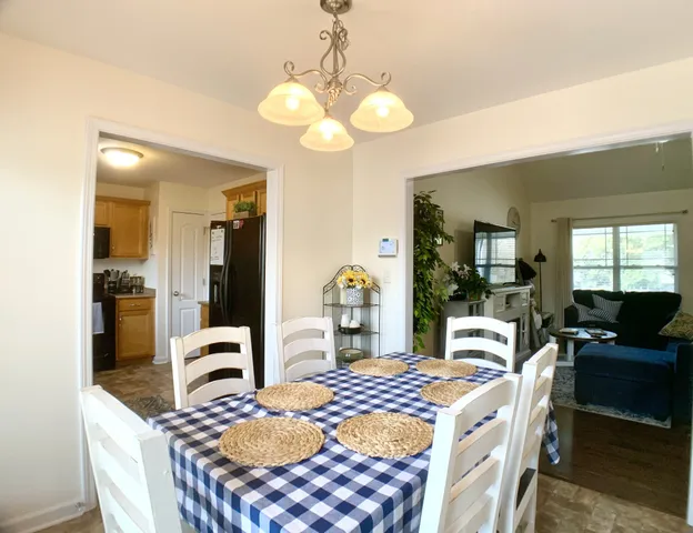 a dining room with wooden floor a chandelier a wooden table and chairs