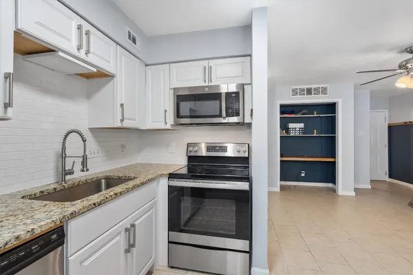 a kitchen with granite countertop a stove sink and microwave
