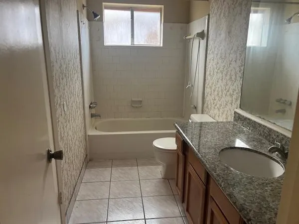 a bathroom with a granite countertop sink a toilet and shower