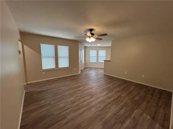 a view of an empty room with a window and wooden floor