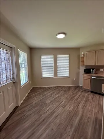 a view of an empty room with a window and wooden floor