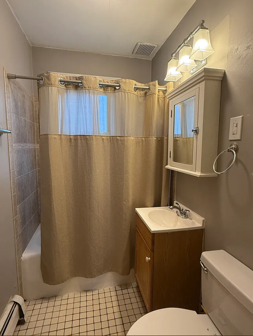 6010 West Seminole Street, Unit 2 Chicago, IL 60646 - Photo 9 of 14 a bathroom with a sink a toilet a mirror and shower