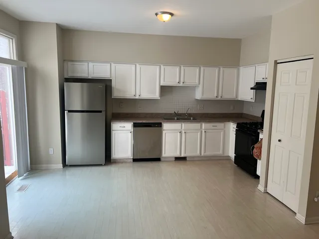 a kitchen with stainless steel appliances a refrigerator a stove a sink and white cabinets