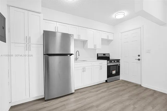a kitchen with a refrigerator a stove top oven and wooden floor