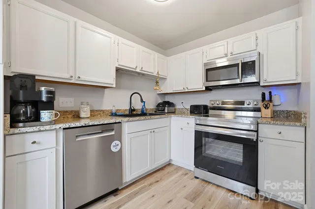 a kitchen with stainless steel appliances granite countertop a stove top oven a sink dishwasher and cabinets with wooden floor