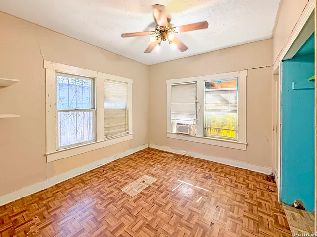 a view of an empty room with window and wooden floor