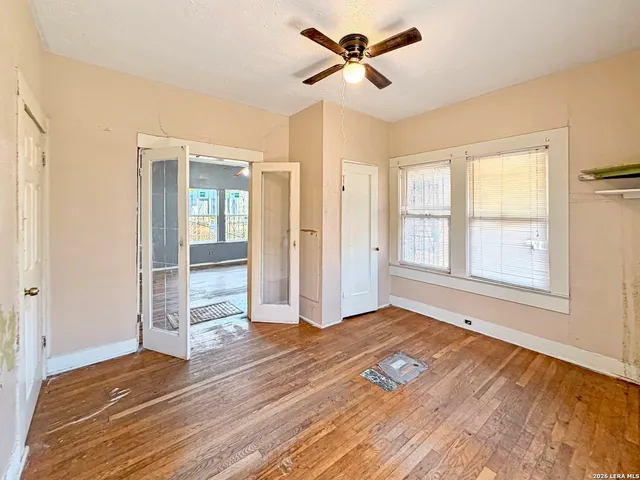 a view of empty room with wooden floor and fan