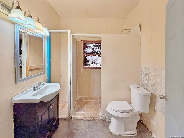 a bathroom with a granite countertop sink toilet a mirror a vanity and shower