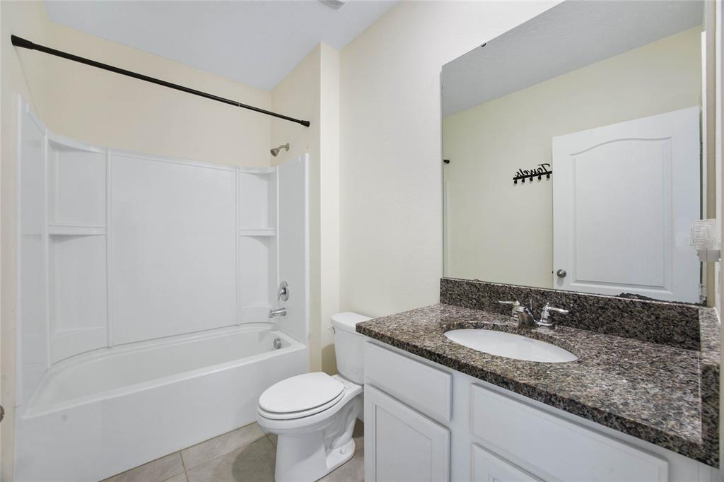 652 Greymount Street Davenport, FL 33837 - Photo 19 of 30 a bathroom with a granite countertop sink toilet and shower