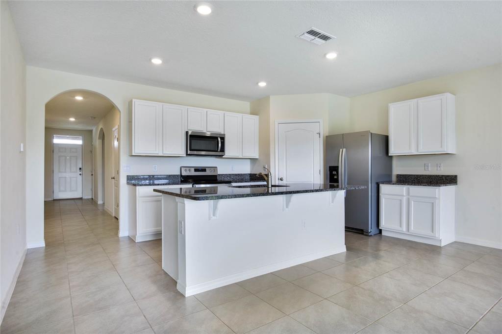 652 Greymount Street Davenport, FL 33837 - Photo 8 of 30 a large kitchen with stainless steel appliances a refrigerator and a stove top oven
