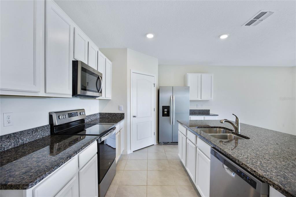 652 Greymount Street Davenport, FL 33837 - Photo 9 of 30 a kitchen with stainless steel appliances granite countertop a sink stove and refrigerator
