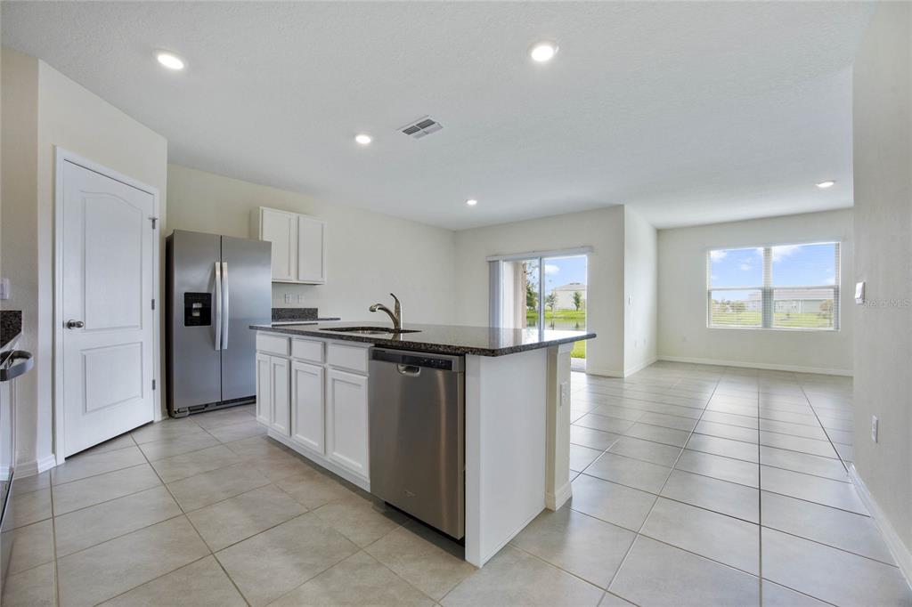 652 Greymount Street Davenport, FL 33837 - Photo 10 of 30 a kitchen with stainless steel appliances granite countertop a refrigerator and a sink
