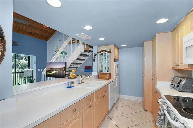 a large white kitchen with stainless steel appliances granite countertop a sink and a stove