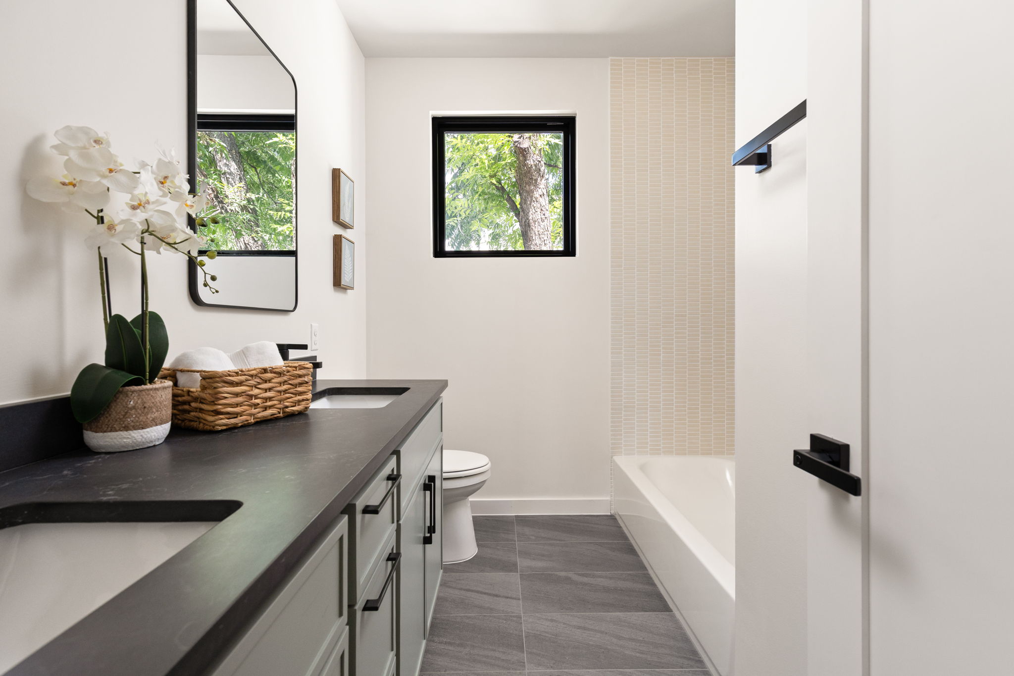 2717 Lyons Road, Unit 1 Austin, TX 78702 - Photo 26 of 40 A refined bathroom featuring a sleek double vanity, modern fixtures, and a bright window overlooking green foliage.