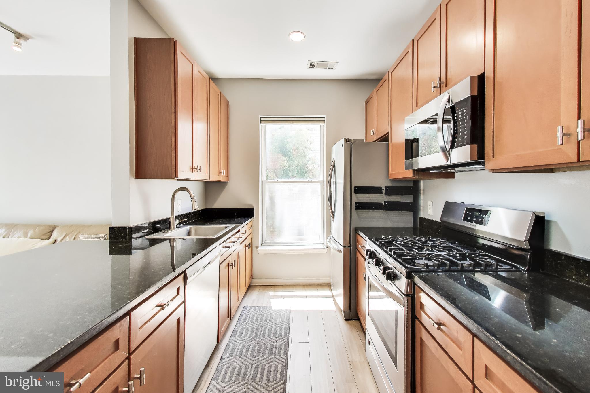 8045 Newell Street, Unit 118 Silver Spring, MD 20910 - Photo 17 of 39 a kitchen with stainless steel appliances granite countertop a stove a sink and a refrigerator