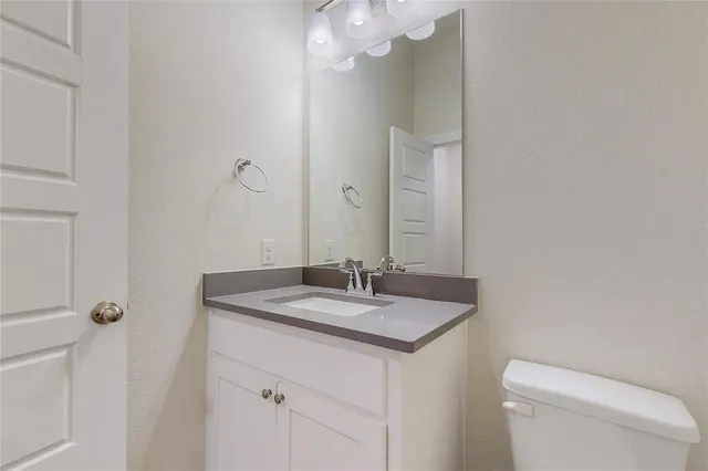 a bathroom with a granite countertop sink a toilet and mirror