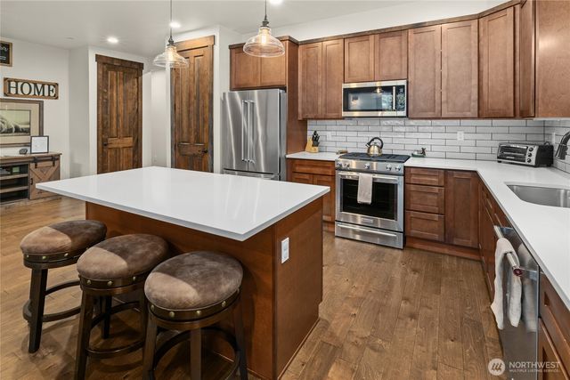 a kitchen with kitchen island a stove a sink a refrigerator with a dining table and chairs