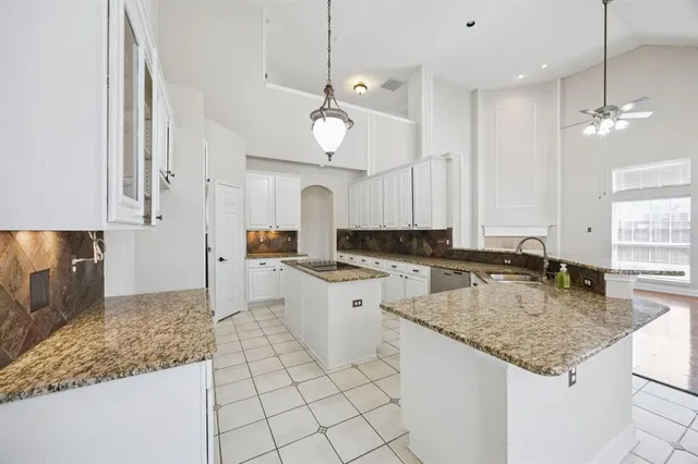 a large kitchen with kitchen island granite countertop a sink a center island and cabinets